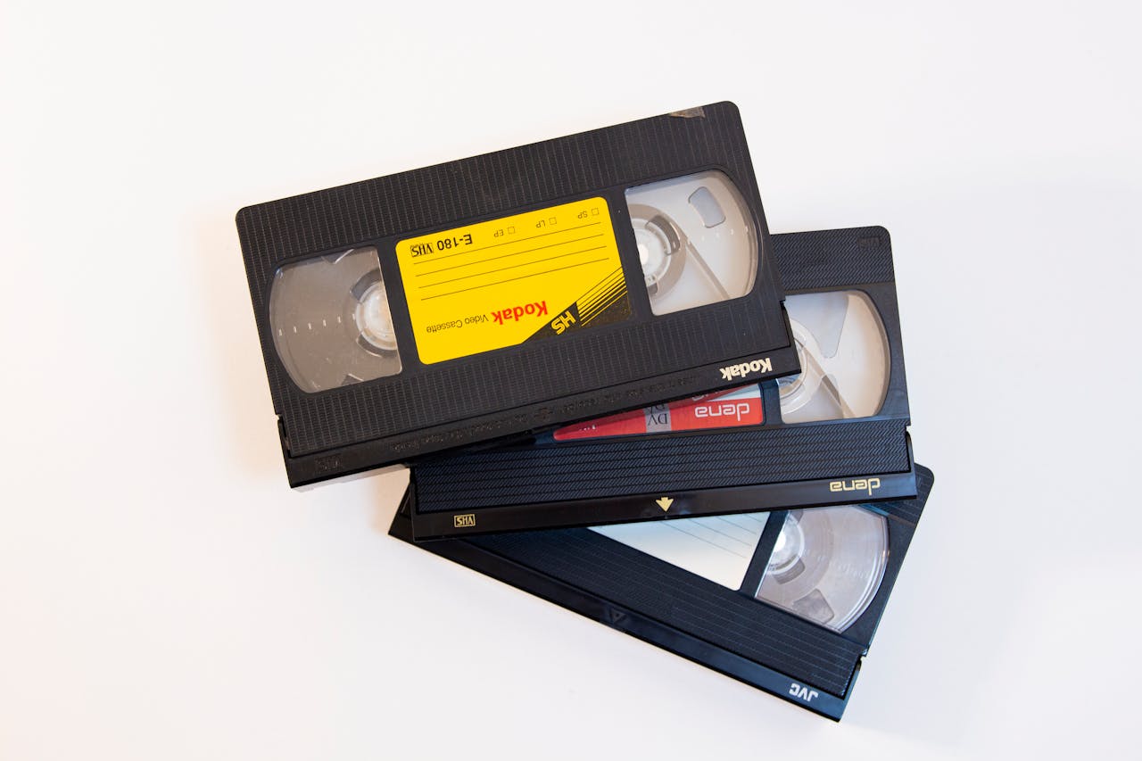 features-03 Close-up of a stack of vintage VHS video cassette tapes on a white background, symbolizing nostalgia.